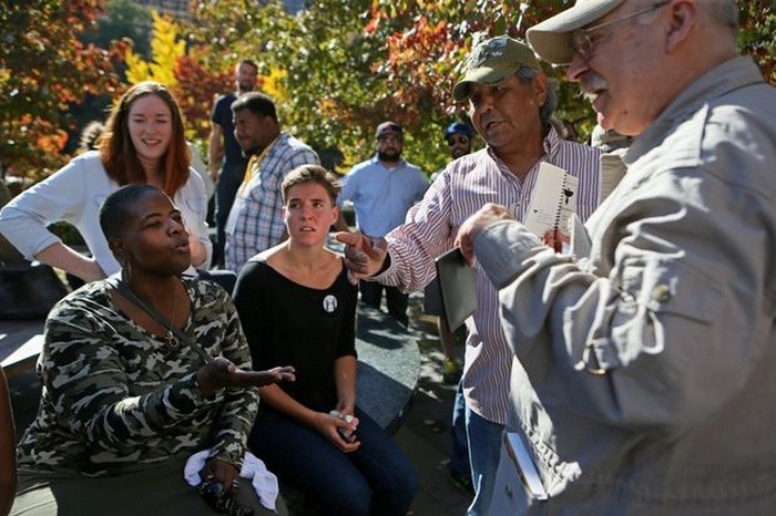 Шонда Урен (слева) делится своими опасениями со сторонником открытого ношения оружия Роном Скайуотером (второй справа) и Джоном Рикоффом (справа на заднем плане). Они обсуждают то, какую роль играет цвет кожи во время демонстраций в поддержку или против оружия.