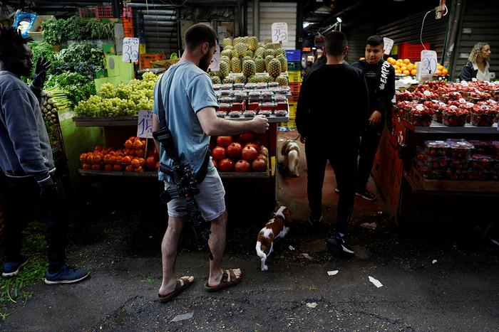 Чоловік із гвинтівкою гуляє зі своїми собаками на ринку в Тель-Авіві, Ізраїль, 8 лютого 2024 року. Фото: Reuters 