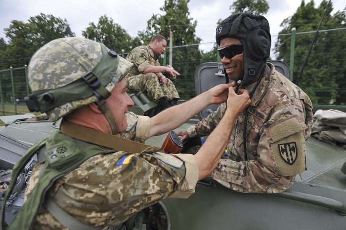 Ein Ukrainer zeigt einem Amerikaner, wie man eine Panzerhaube à la russe anlegt