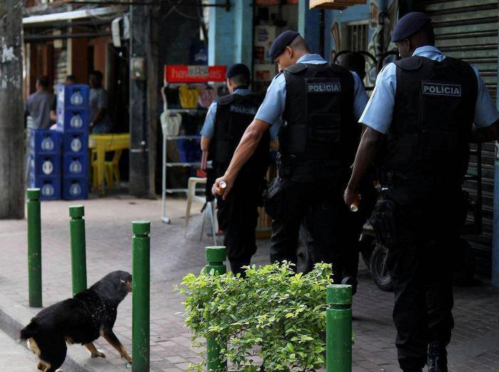 Бразильский полицейский применяет газовый баллончик против собаки.