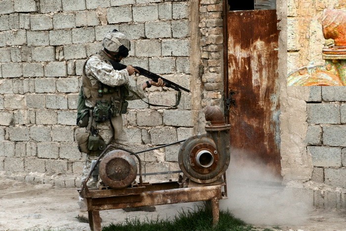 Американский солдат готовится взломать дверь при помощи дробовика