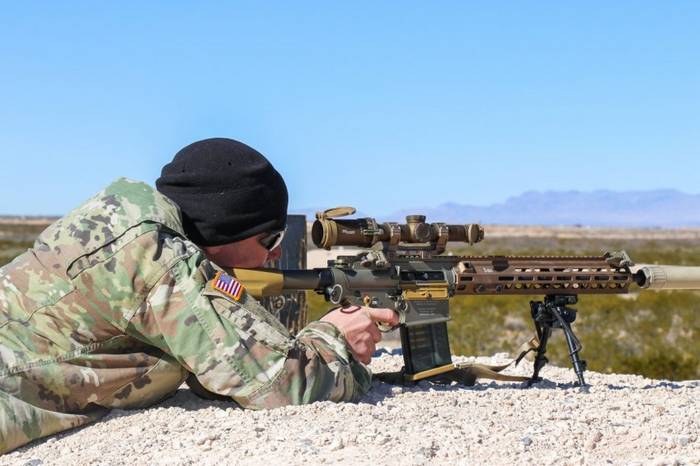 Испытания винтовки SDM-R с оптическим прицелом Sig TANGO6 и глушителем OSS Helix HX-QD 762 на военной базе Форт Блисс. Винтовка имеет складные механические прицельные приспособления, смещённые на позицию «1 час».