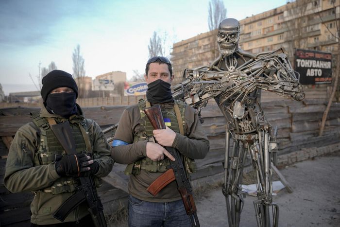 Українські тероборонівці-добровольці позують із Термінатором, зробленим із деталей авто трансмісії, поблизу контрольно-пропускного пункту в Києві, Україна, 25 березня 2022  © Vadim Ghirda / AP